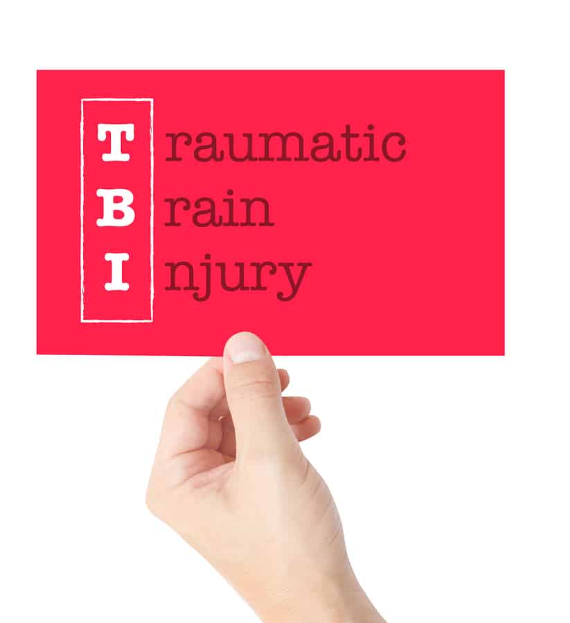 Traumatic Brain Injury explained on a card held by a hand